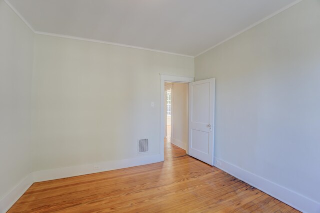 unfurnished room featuring ornamental molding and light wood-type flooring