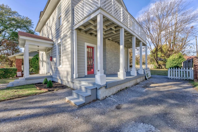 property entrance featuring covered porch and a balcony