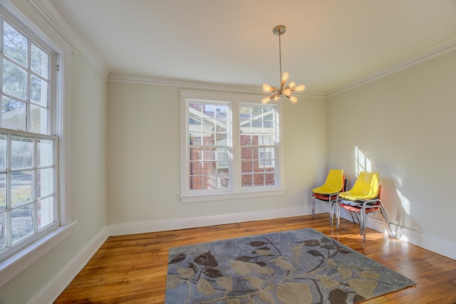 sitting room featuring hardwood / wood-style flooring, a healthy amount of sunlight, crown molding, and an inviting chandelier