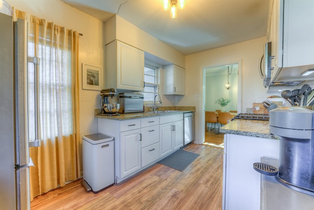 kitchen with light stone countertops, sink, stainless steel appliances, light hardwood / wood-style flooring, and white cabinets