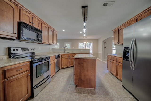 kitchen with appliances with stainless steel finishes, sink, pendant lighting, a kitchen island, and light tile patterned flooring