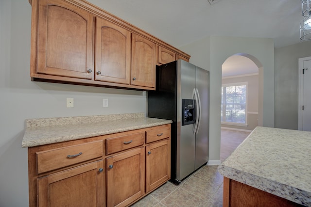 kitchen with stainless steel fridge, light tile patterned floors, and ornamental molding