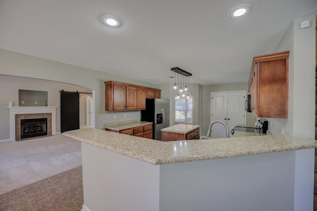 kitchen featuring kitchen peninsula, stainless steel fridge with ice dispenser, light colored carpet, and a kitchen island