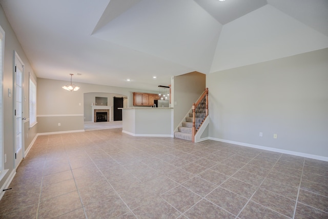 unfurnished living room featuring a chandelier, light tile patterned floors, and vaulted ceiling