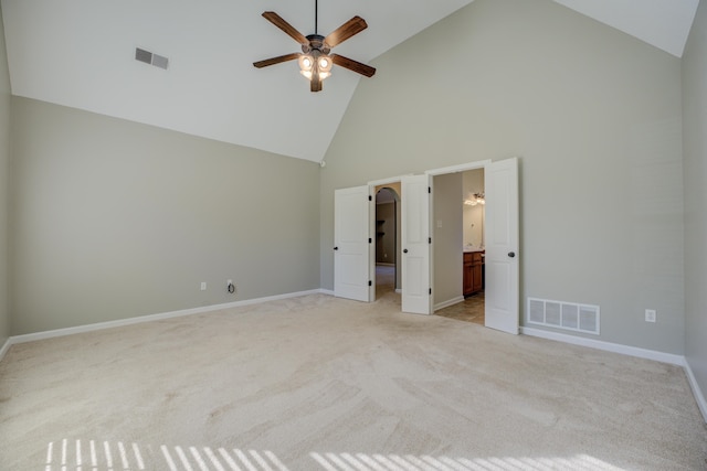 unfurnished bedroom featuring ensuite bathroom, high vaulted ceiling, light carpet, and ceiling fan