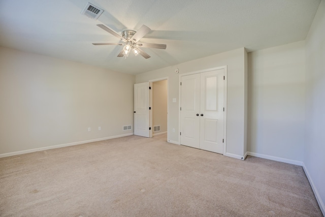 unfurnished bedroom featuring ceiling fan, light colored carpet, and a closet