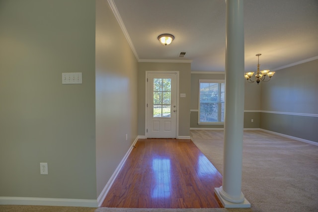 doorway to outside with hardwood / wood-style floors, ornate columns, crown molding, and an inviting chandelier