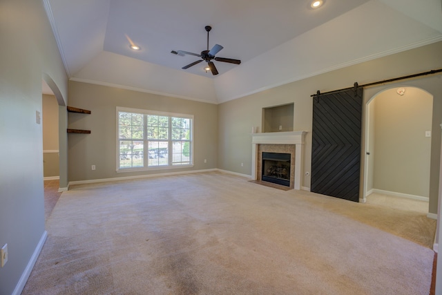 unfurnished living room featuring light colored carpet, ceiling fan, crown molding, and a tiled fireplace