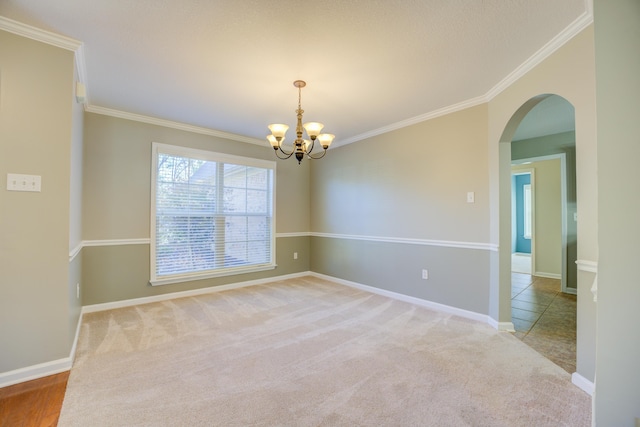 carpeted empty room featuring a notable chandelier and ornamental molding