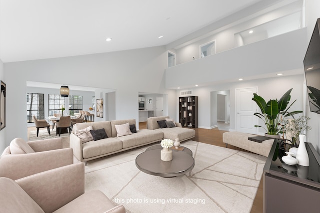 living room featuring high vaulted ceiling and light wood-type flooring