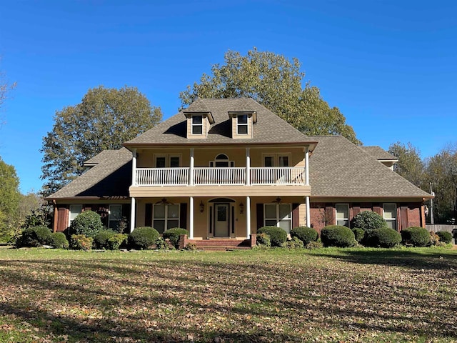 view of front of house featuring a balcony and a front lawn