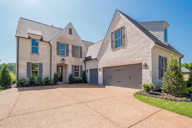 traditional-style house featuring driveway, an attached garage, and stone siding