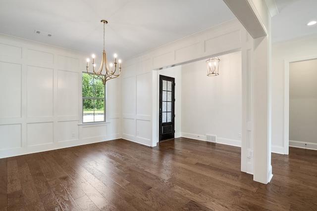 unfurnished dining area featuring dark hardwood / wood-style flooring, crown molding, and a notable chandelier