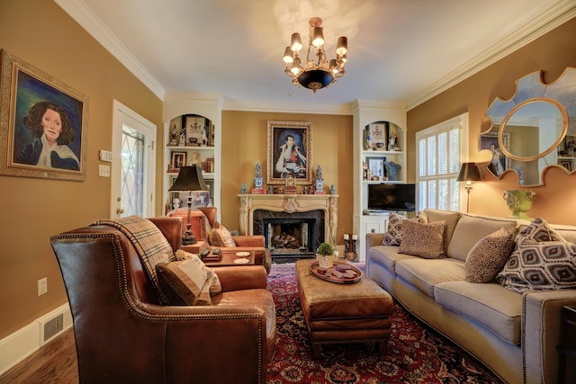 living room featuring an inviting chandelier, hardwood / wood-style flooring, built in shelves, a premium fireplace, and ornamental molding