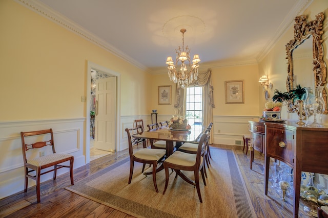 dining room featuring wood-type flooring, ornamental molding, and a notable chandelier