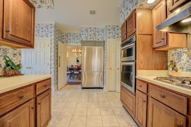 kitchen featuring a chandelier, appliances with stainless steel finishes, light tile patterned floors, and ornamental molding