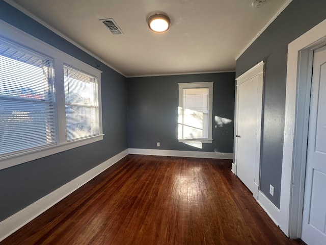 unfurnished bedroom featuring dark hardwood / wood-style flooring, crown molding, and multiple windows