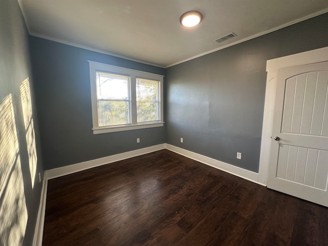 empty room featuring ornamental molding and dark wood-type flooring