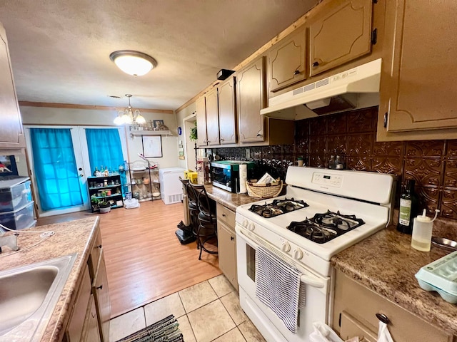 kitchen featuring hanging light fixtures, light wood-type flooring, white gas range, ornamental molding, and a chandelier