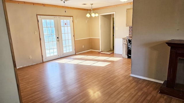 unfurnished dining area featuring an inviting chandelier, light hardwood / wood-style flooring, and french doors