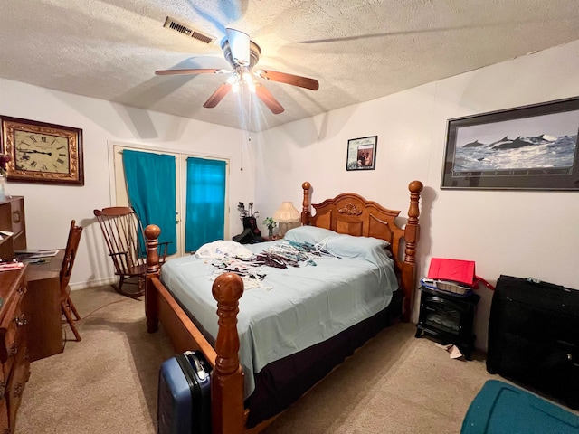 carpeted bedroom featuring ceiling fan and a textured ceiling