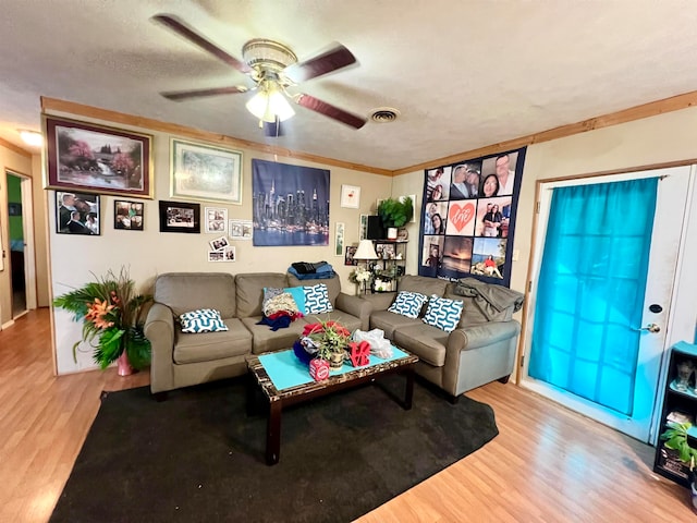 living room featuring ceiling fan, light hardwood / wood-style floors, a textured ceiling, and ornamental molding