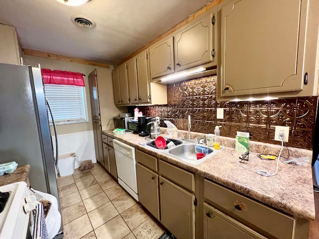 kitchen featuring backsplash, white dishwasher, sink, range, and stainless steel refrigerator