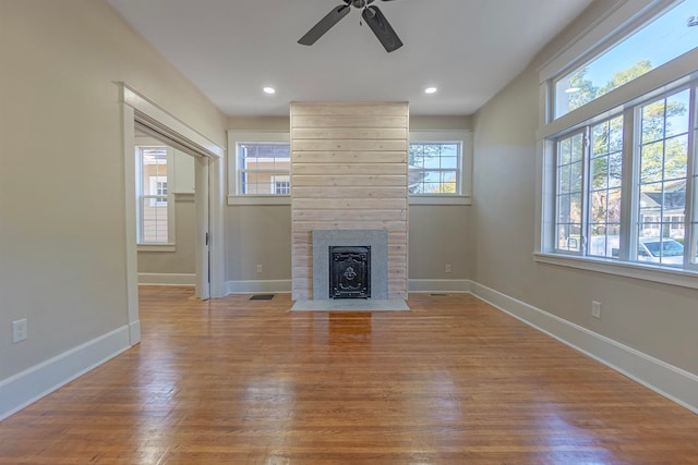 unfurnished living room with light hardwood / wood-style flooring, ceiling fan, and a tiled fireplace