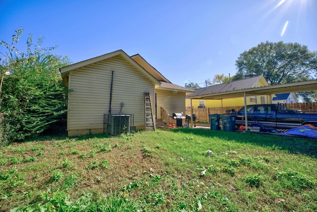 rear view of property with a yard and central air condition unit