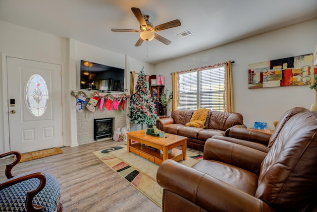 living room with ceiling fan, light hardwood / wood-style floors, and a brick fireplace