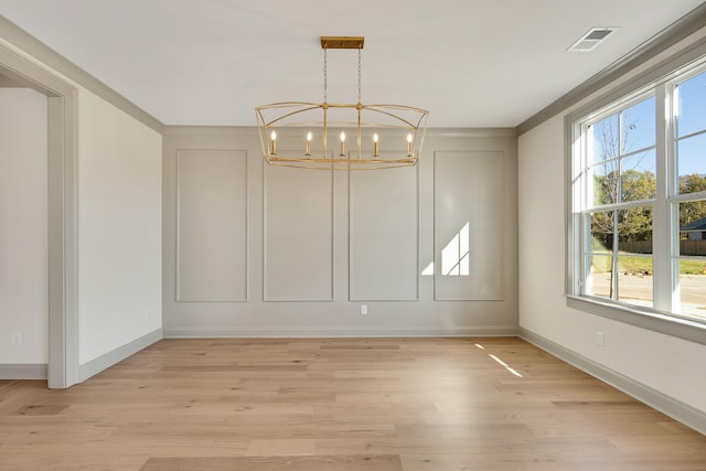 unfurnished dining area with ornamental molding, light hardwood / wood-style floors, and a notable chandelier