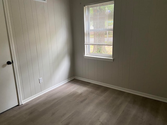 empty room with light hardwood / wood-style floors, plenty of natural light, and wood walls