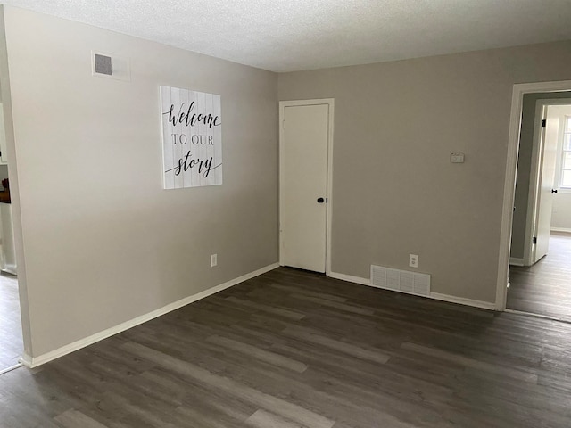 unfurnished room with dark hardwood / wood-style floors and a textured ceiling