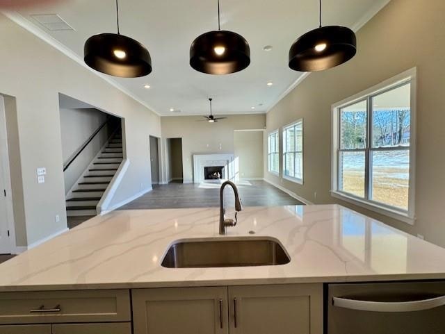 kitchen featuring light stone counters, decorative light fixtures, open floor plan, a sink, and dishwasher