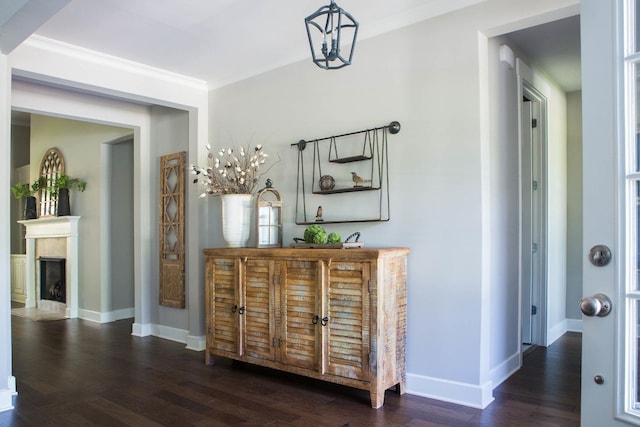 hall featuring dark wood-type flooring, crown molding, and baseboards