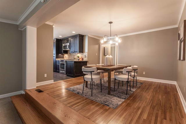 dining room featuring crown molding, dark hardwood / wood-style flooring, and a notable chandelier