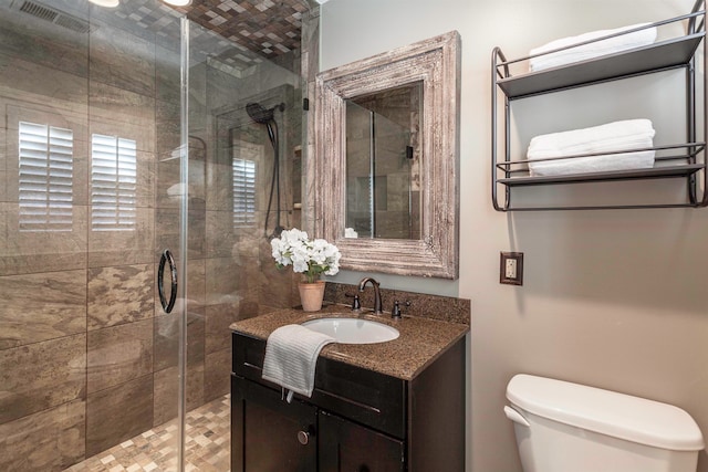 bathroom featuring vanity, toilet, and a shower with shower door