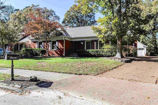 view of front facade with a garage, an outbuilding, and a front lawn