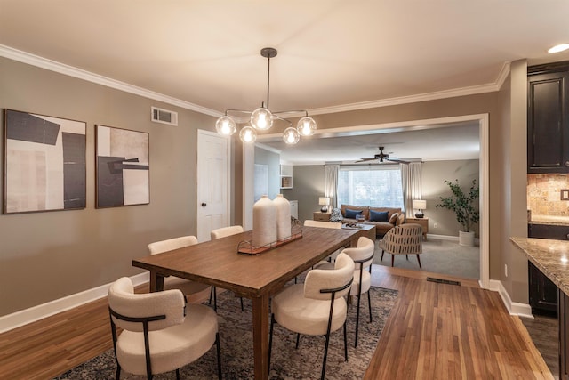 dining space featuring ceiling fan with notable chandelier, dark hardwood / wood-style flooring, and ornamental molding