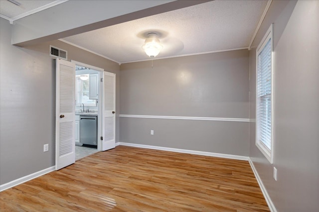 empty room with hardwood / wood-style floors, ornamental molding, a textured ceiling, and a wealth of natural light