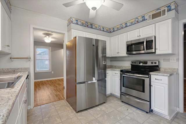 kitchen featuring ceiling fan, light wood-type flooring, a textured ceiling, white cabinetry, and stainless steel appliances