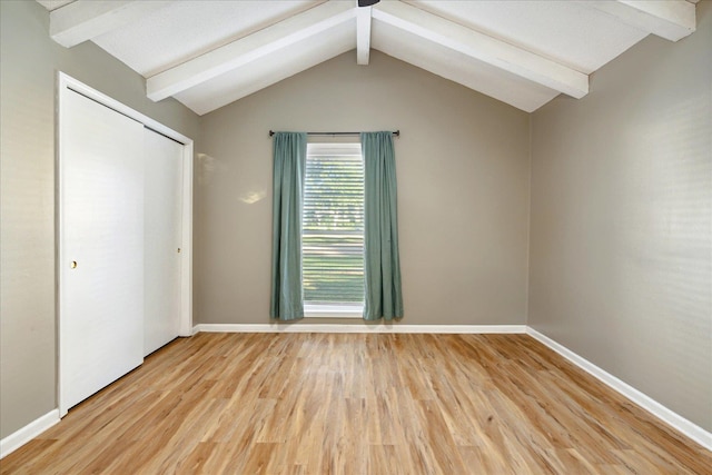 unfurnished bedroom featuring lofted ceiling with beams, light hardwood / wood-style floors, and a closet