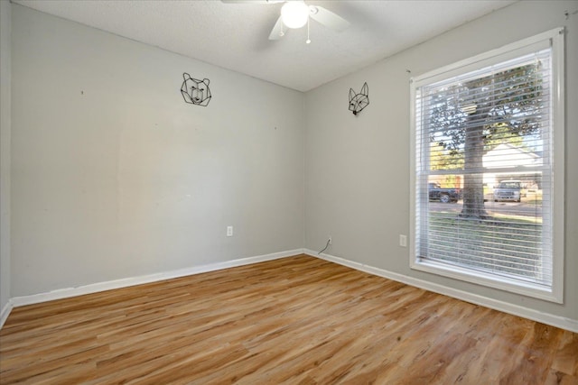 empty room featuring a textured ceiling, light wood-type flooring, and ceiling fan