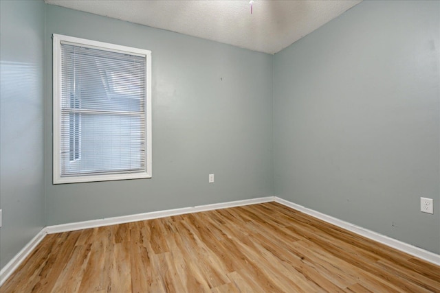 empty room with a textured ceiling, hardwood / wood-style flooring, and a wealth of natural light