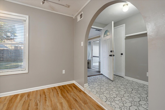 empty room with light hardwood / wood-style floors, a textured ceiling, and ornamental molding