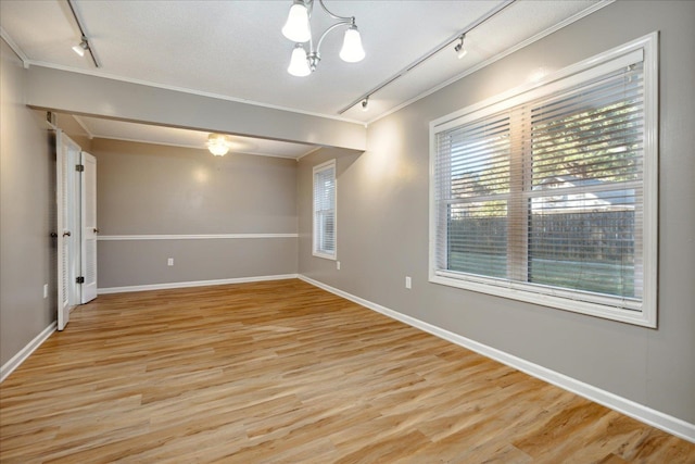 unfurnished room featuring a notable chandelier, light hardwood / wood-style floors, ornamental molding, and track lighting