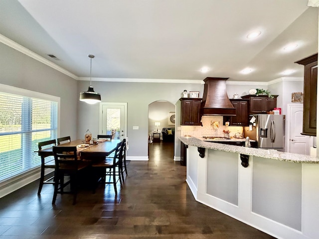 kitchen with pendant lighting, a breakfast bar, custom range hood, dark hardwood / wood-style flooring, and stainless steel fridge with ice dispenser