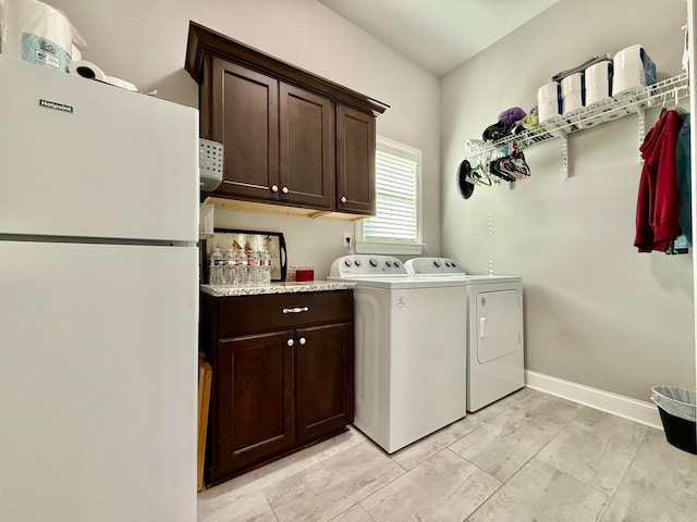 clothes washing area with separate washer and dryer and cabinets