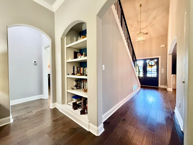 foyer entrance featuring dark hardwood / wood-style flooring, french doors, crown molding, and an inviting chandelier