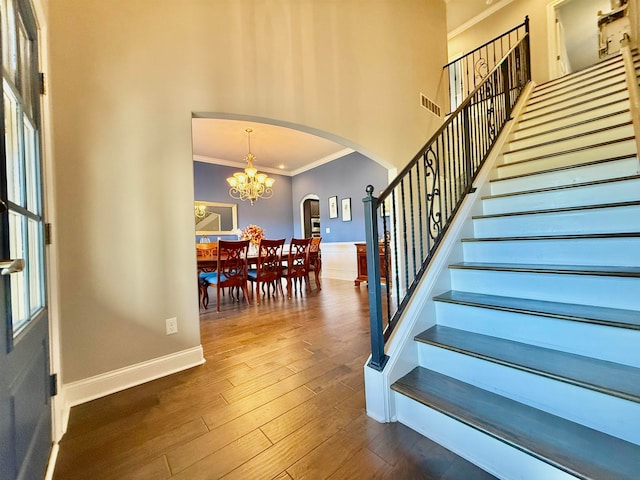 stairs featuring hardwood / wood-style floors, an inviting chandelier, and crown molding